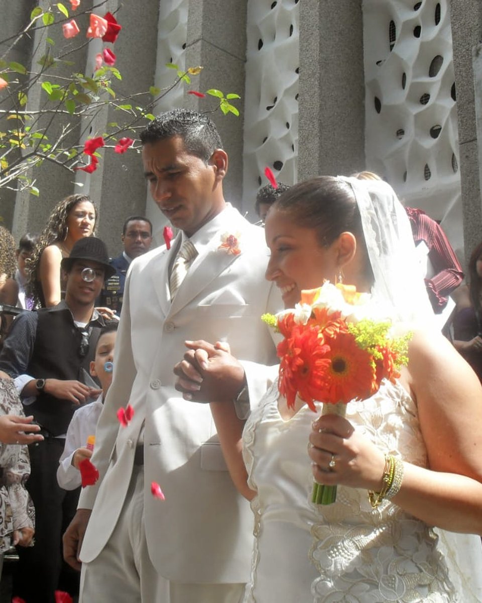 Los novios abrazados, ella con vestido de encaje y él con traje beige